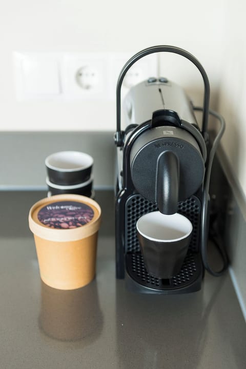  A modern hotel room amenity setup, featuring a compact espresso machine with stylish cups, ready to provide guests with a fresh, energizing start to their day.