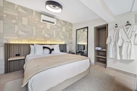 Modern and minimalist bedroom featuring a large, comfortable bed with crisp white linens and plush pillows, accented by a stylish beige headboard.