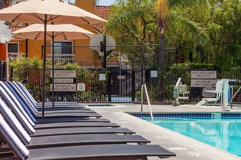 Lounge comfortably poolside with shaded seating and calm water.