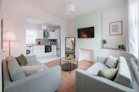 A clean, relaxing space — unwind in the spacious living room with a plush sofa set and a smart TV for the ultimate comfort and entertainment.