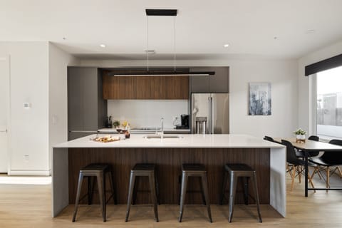 1st Floor: Fully equipped modern kitchen featuring culinary essentials, stainless steel appliances, island bar seating, and a dining area.