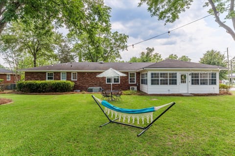 Fenced backyard with hammock, outdoor seating and lights.