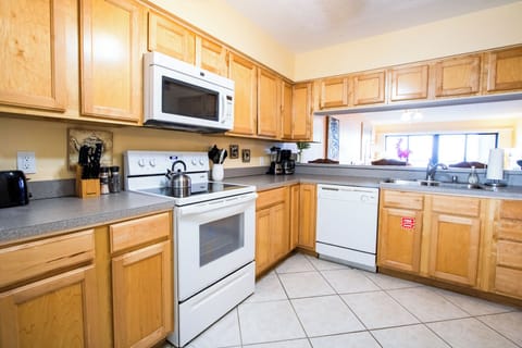 Open kitchen that well-equipped with appliances including a refrigerator, stove, oven, and microwave, making meal preparation. Ample counter space provides plenty of room for cooking and serving.