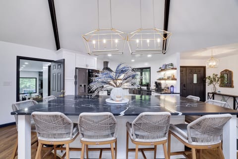 Chic kitchen with marble island, gold lights, and woven barstools.