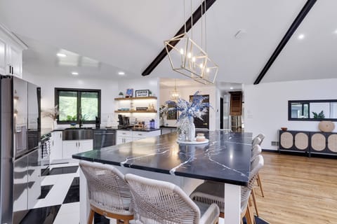 Modern kitchen with marble island, gold lights, and sleek open shelving.