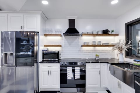 Bright modern kitchen with black marble counters and wood floating shelves.