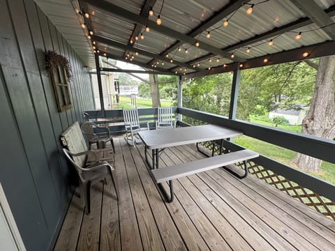 The covered deck includes ample seating plus a picnic table and string lights.