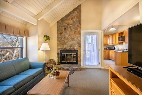 Living area with stone fireplace and private deck access