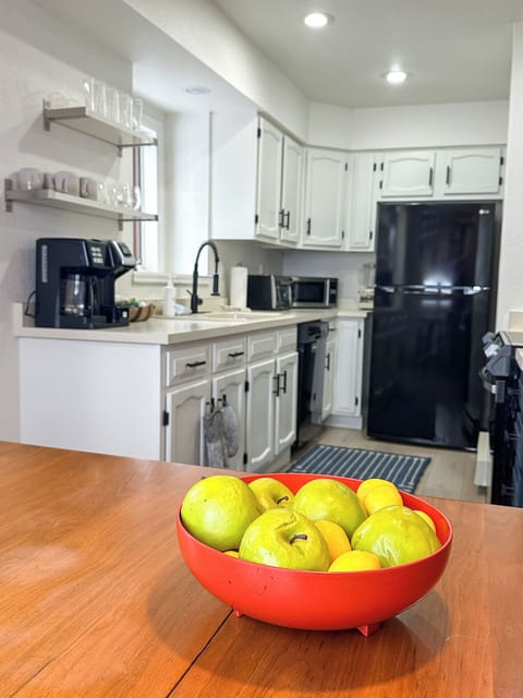 - Well equipped kitchen with black appliances, white cabinets, and open shelves - Modern coffee maker and microwave make mornings simple and delicious - Fresh fruit and cheerful decor keep the space homey, bright, and welcoming