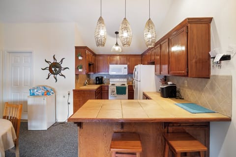 This kitchen area is warm and inviting. The overhead lighting adds a touch of elegance, creating the perfect ambiance for both casual meals and entertaining guests.