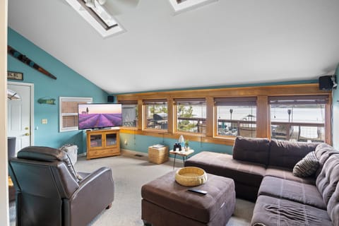 Spacious living area with panoramic lakeside views, cozy seating, and natural light from the outdoors, perfect for relaxing and enjoying the serene waterfront setting.