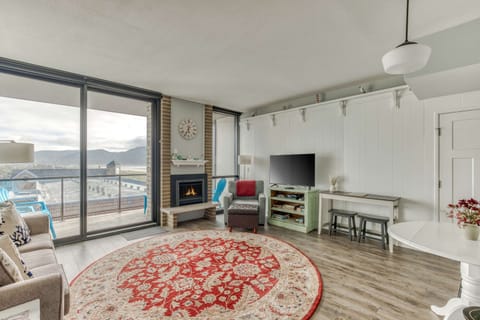 Warm and inviting living room featuring a cozy fireplace and plenty of seating wrapped by large windows allowing natural light to enter.