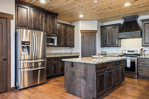 - Fully equipped kitchen with island workspace  
- Stainless steel fridge and modern appliances  
- Dark wood cabinetry creates mountain lodge style