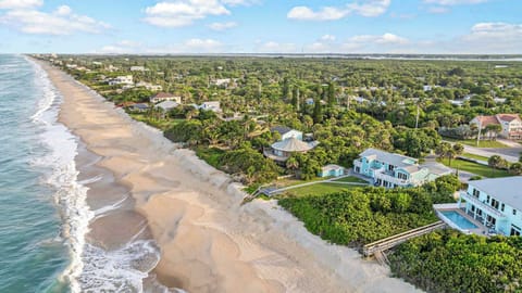 Aerial view of a coastal neighborhood with direct access to a sandy beach and ocean waves.