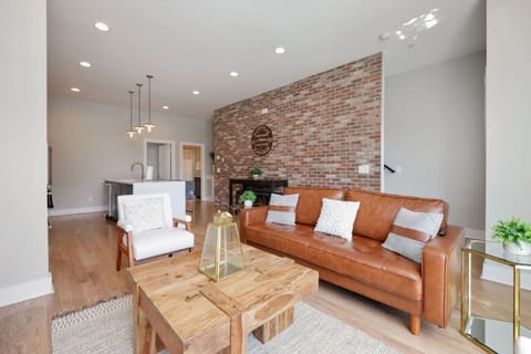 Living room with leather sofa, exposed brick accent wall, wooden coffee table, and pendant light