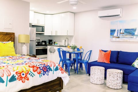 A glimpse into our studio reveals a welcoming space where a queen-sized bed and a convertible couch promise comfort. The kitchen, with its modern amenities, stands nearby, while a stylish 4-seater dining table completes the picture.