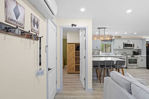 This inviting space seamlessly connects the living room, kitchen, and hallway, creating a spacious yet cozy atmosphere. The warm tones and stylish accents make it feel just like home.