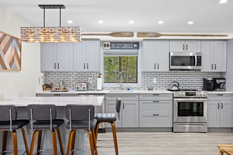 This modern kitchen is fully equipped with stainless steel appliances, sleek gray cabinets, and subway tile backsplash. The warm wood tones and rustic oars give it a charming cabin feel.