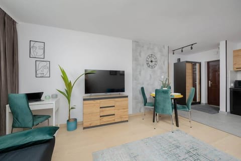 A cozy living room with a stylish grey couch, wooden furniture, and decorative plants for a modern touch. Perfect for relaxing or entertaining guests.