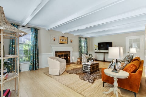 Spacious living room with plush couches, indoor fireplace, TV, and books