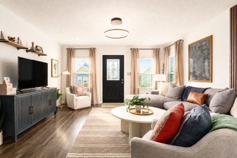 Bright, cozy living room with large sectional, TV, and abundant natural light