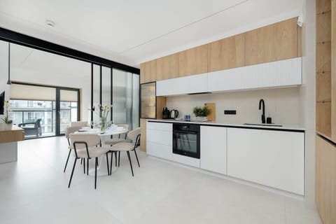 A small modern kitchen with wood cabinetry and black appliances. Clean lines and efficient use of space.