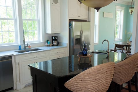 Kitchen with large windows and kitchen island with seating and prep sink.