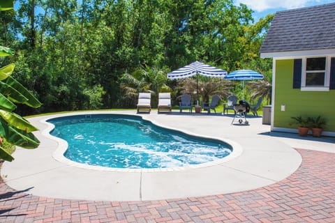 Private Pool with lounge chairs and umbrellas along with a charcoal grill.