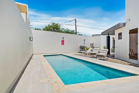 The backyard features a sleek, pool with crystal-clear water, perfect for relaxing or swimming laps - Lounge chairs and a barbecue area provide a perfect setting for outdoor gatherings - Enclosed by walls, the area ensures privacy and tranquility
