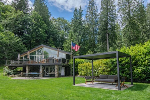 Louvered pergola overlooks the pickleball court and yard beside the house.