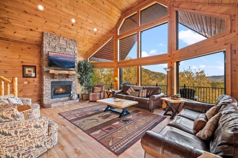 The spacious living room includes a stunning wall of windows as well as a stone fireplace, large Smart TV, and plenty of comfortable furniture.