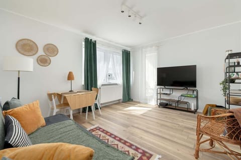 Cosy living room with sofa and TV. Soft curtains and tartan accessories add warmth and a unique touch.