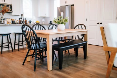 The wood dining table is paired with a black bench on one side and four black chairs on the other, creating a stylish and functional dining space. The mix of materials and colors adds a modern, polished touch.