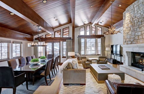 Gather in the expansive living room, offering comfortable seating, a beautiful stone fireplace, and large windows providing picturesque views of the surroundings.