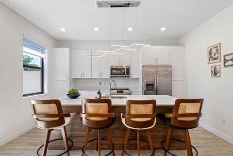 Experience the elegance of our kitchen with tons of white cabinetry, a center counter with a built-in sink, and an array of bar tools to enhance your cooking and entertaining