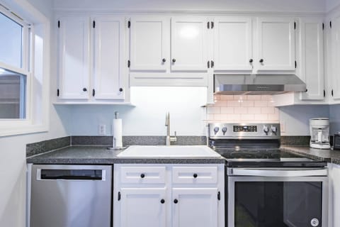 The kitchen features a stainless steel dishwasher, range and hood.