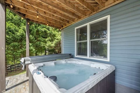A private hot tub on a covered patio surrounded by lush greenery, perfect for unwinding in a tranquil lakeside setting.