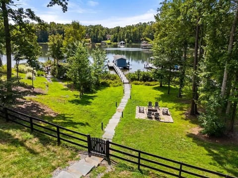 A picturesque lakefront property featuring a serene dock, lush greenery, and a cozy fire pit, perfect for relaxation and outdoor enjoyment.