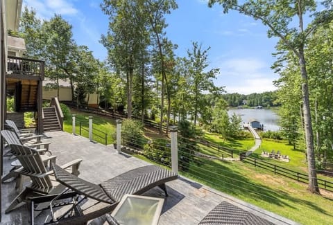 Spacious outdoor deck with lounge chairs overlooking a lush, tree-filled yard and serene lake views, offering a perfect spot for relaxation