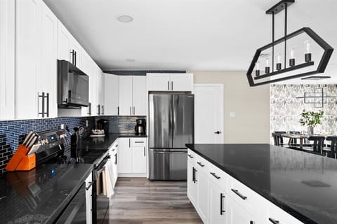 Our modern kitchen features white cabinets, black countertops, and a blue tile backsplash