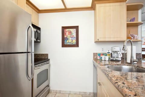 With speckled granite, pale wood, and citrus-bright accents, this kitchen sings with sunny island personality    