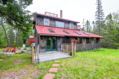 View of the front of the house. There are chairs by the fire pit.