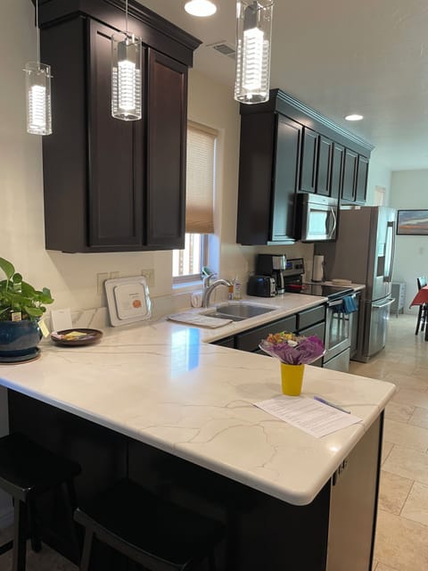 Full kitchen with new quartz countertops and lighting.  Pantry on opposite wall.