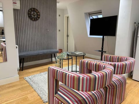 - Chic living area with striped chairs and wall décor  
- Glass coffee tables add modern touch to the room  
- Comfortable setup designed for social relaxation  