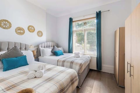 - Twin bedroom with cozy beds and soft linens  
- Bright window with natural light and garden view  
- Relaxing space with teal accents and modern comfort  