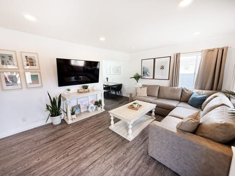 Relax in the bright and inviting living room featuring a large sectional sofa, stylish coastal decor, and a flat-screen smart TV for movie nights.