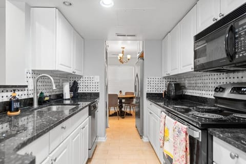 Kitchen: Kitchen featuring white cabinets, a black quartz countertop, and an array of kitchen supplies. Includes brand new appliances: coffee machine, air fryer, blender, toaster, and more.