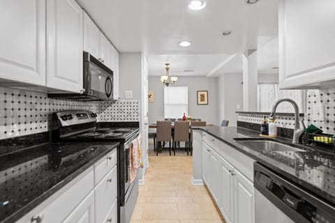 Kitchen: Kitchen featuring white cabinets, a black quartz countertop, and an array of kitchen supplies.