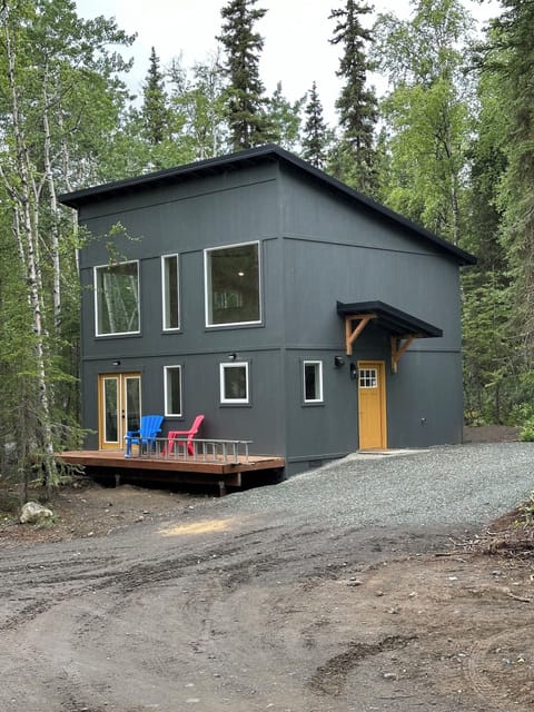 Large cabin drive up exterior featuring a charming wooden wall and two cozy chairs for enjoying the surrounding beauty.