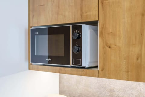 A modern kitchenette with wooden cabinets, equipped with a coffee machine and kettle on the countertop.